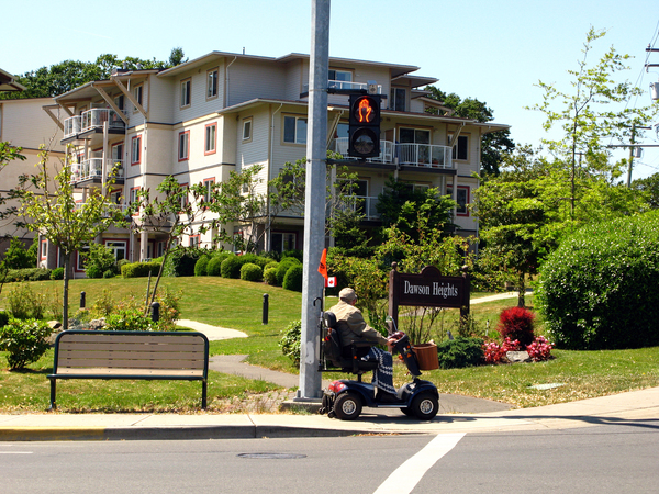 Multi unit rental building with a park in front and a person on a people mover